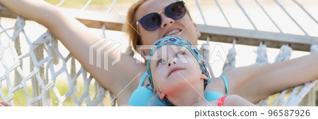 Mother and daughter lay on hammock in shade, enjoy life, time with family, mother daughter time Mother and daughter lay on hammock in shade, enjoy life, time with family, mother daughter time 96587926