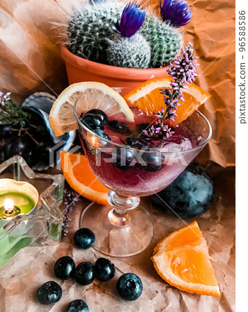 Blackberry alcohol drink with ice cube in glass surrounded with fruits and cactus on the background Blackberry alcohol drink with ice cube in glass surrounded with fruits and cactus on the background 96588586