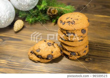 Chocolate chip cookies in front of Christmas decoration on wooden table Chocolate chip cookies in front of Christmas decoration on wooden table 96589523