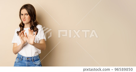 Young woman cringe, shaking hands to decline, reject disgusting bad offer, standing over beige background 96589850