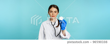 Image of woman doctor, listening patient lungs with stethoscope, doing medical checkup in clinic, standing over blue background Image of woman doctor, listening patient lungs with stethoscope, doing medical checkup in clinic, standing over blue background 96590108