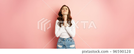 Please. Young stylish girl begging, holding hands in pray, need help, pleading, supplicating, standing against pink background 96590128