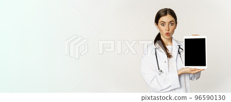 Image of woman doctor, female healthcare worker showing online medical website, digital tablet screen and smiling, standing in white coat over white background 96590130