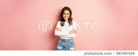 Spring and beauty. Young beautiful and stylish female model posing against pink background, cross arms on chest, smiling happy Spring and beauty. Young beautiful and stylish female model posing against pink background, cross arms on chest, smiling happy 96590384