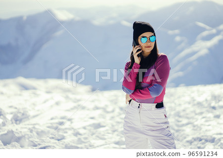 young and stylish brunette in the snowy mountains use the phone 96591234