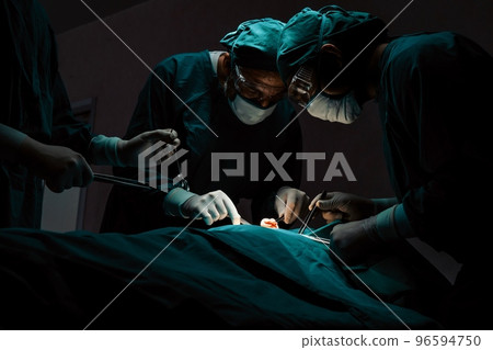 Surgical team performing surgery to patient in sterile operating room. Surgical team performing surgery to patient in sterile operating room. 96594750