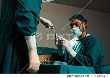 Surgeon fill syringe from vial for surgical procedure at sterile operation room. 96594878