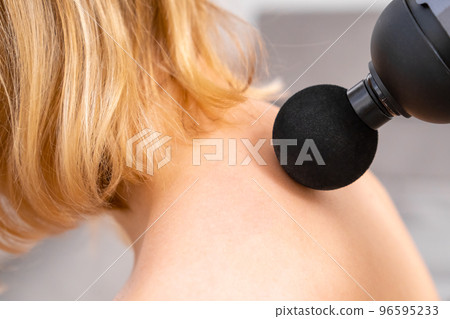 Blonde hair woman massaging a neck using a massage gun. Sport recovery concept.  96595233