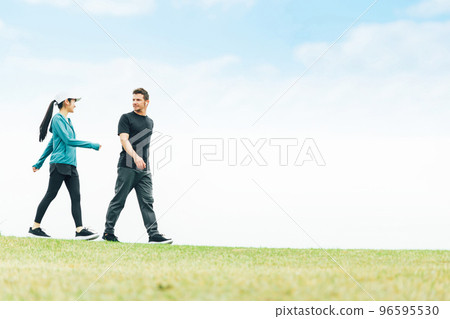 Men and women wearing sportswear walking, strolling and doing aerobic exercise in the park for health Men and women wearing sportswear walking, strolling and doing aerobic exercise in the park for health 96595530