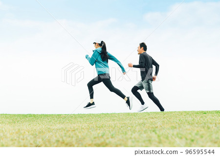 Rear view of Asian men and women wearing sportswear running at speed in the park 96595544