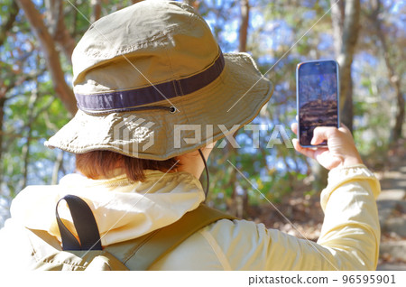 登山時拍照的徒步旅行者女人 登山時拍照的徒步旅行者女人 96595901