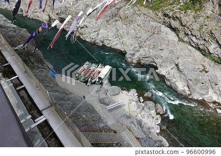 A lot of carp streamers and a clear river flowing under the cliffs and a sightseeing boat A lot of carp streamers and a clear river flowing under the cliffs and a sightseeing boat 96600996