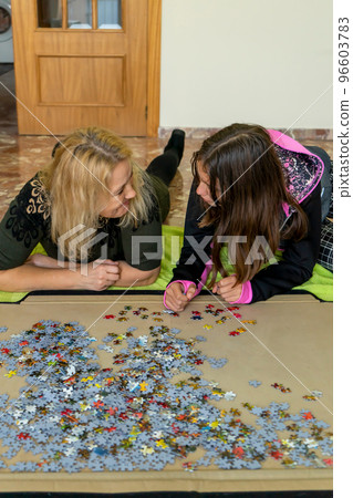 Mother and daughter lying on the floor doing a puzzle together while having a nice time on a girls night out 96603783