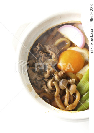 Overhead view of hot miso stewed udon with beef, shimeji mushrooms, long onion, kamaboko, and egg yolk on a white background Overhead view of hot miso stewed udon with beef, shimeji mushrooms, long onion, kamaboko, and egg yolk on a white background 96604228