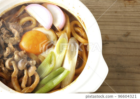 A bird's-eye view of hot miso stewed udon with beef, shimeji mushrooms, green onions, kamaboko, and egg yolk 96604321