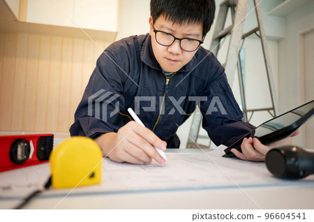 Asian male Interior worker working with architectural drawing 96604541