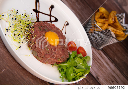 Steak Tartare with vegetables salad and french fries on dish 96605192