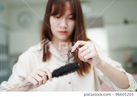 Asian woman have problem with long hair loss attach to comb brush. 96605205