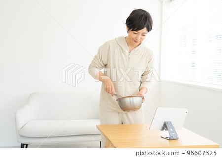 烹調的婦女，當觀看片劑時 96607325