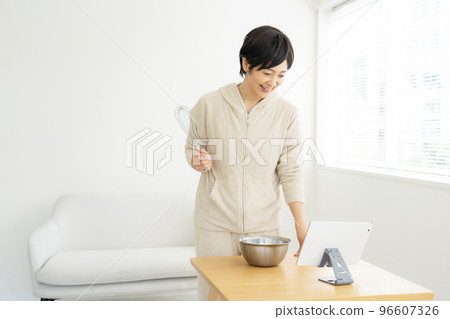 烹調的婦女,當觀看片劑時 烹調的婦女,當觀看片劑時 96607326