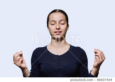Teenage relaxed girl in headphones making meditation gesture with fingers Teenage relaxed girl in headphones making meditation gesture with fingers 96607404