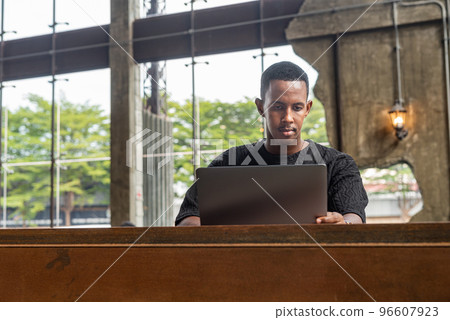 Handsome black man sitting and using laptop computer indoors 96607923