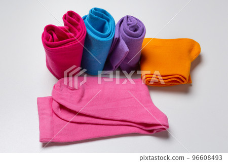 Assortment of socks of different colors, several twisted and the rest partially folded, on a white background 96608493