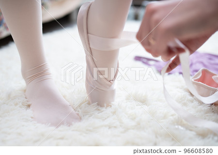 一位母親的手正在為她的孩子穿上足尖鞋 一位母親的手正在為她的孩子穿上足尖鞋 96608580