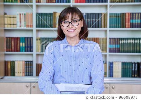 Portrait of female teacher looking at camera in library 96608973