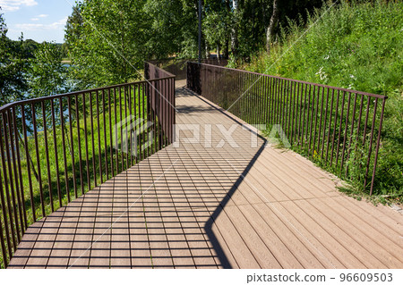 Walking footbridge with a railing laid along the coastal slope near the reservoir Walking footbridge with a railing laid along the coastal slope near the reservoir 96609503