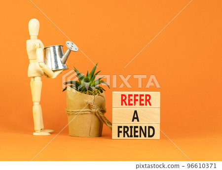 Refer a friend symbol. Concept words Refer a friend on wooden blocks on a beautiful orange table orange background. Businessman model. Business and refer a friend concept. Copy space. 96610371