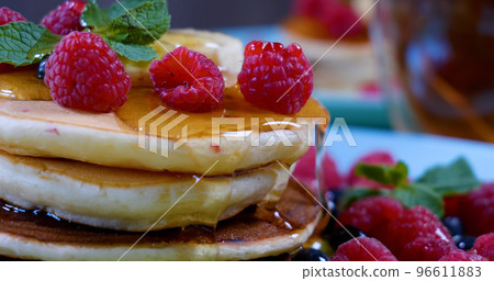 Pancakes with raspberry, banana and a mint leaf and honey 96611883
