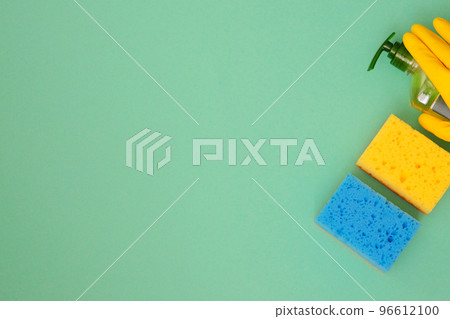 Flat lay cleaning products, copy space. Hand in yellow rubber protective glove with sponges. Service concept. Top view. 96612100