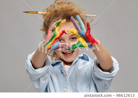 Beautiful little girl with a painted fingers is posing on a gray background. 96612613