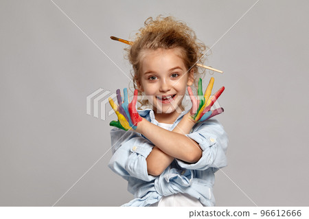 Beautiful little girl with a painted hands is posing on a gray background. 96612666