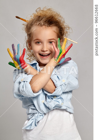Beautiful little girl with a painted hands is posing on a gray background. 96612668