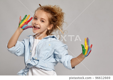 Beautiful little girl with a painted hands is posing on a gray background. Beautiful little girl with a painted hands is posing on a gray background. 96612669