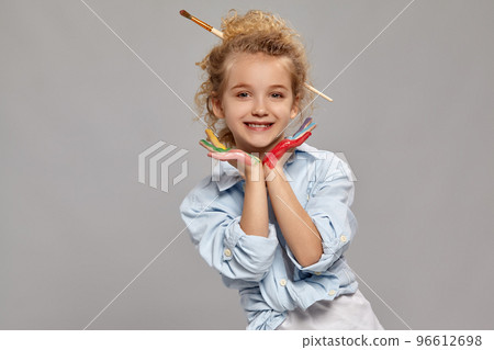Beautiful little girl with a painted hands is posing on a gray background. 96612698