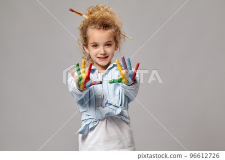 Beautiful little girl with a painted hands is posing on a gray background. 96612726