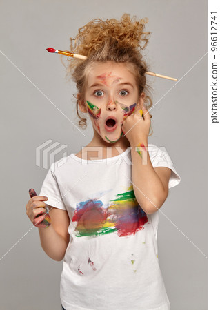 Beautiful little girl with a painted fingers is posing on a gray background. Beautiful little girl with a painted fingers is posing on a gray background. 96612741