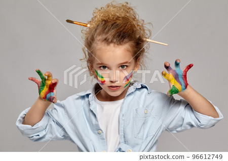 Beautiful little girl with a painted fingers is posing on a gray background. 96612749