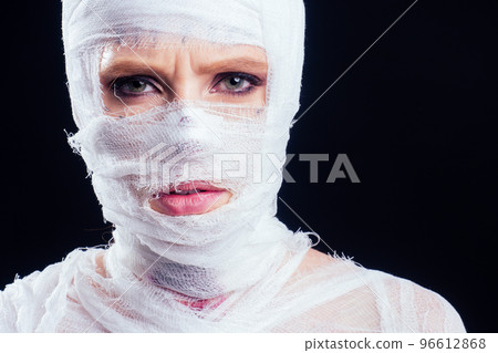 Glamorous mummy woman in bandages all over her body in studio black background. Halloween party or plastic surgery victim concept 96612868