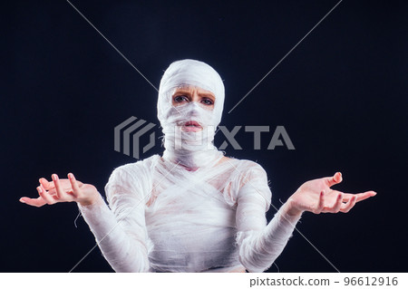 Glamorous mummy woman in bandages all over her body in studio black background. Halloween party or plastic surgery victim concept Glamorous mummy woman in bandages all over her body in studio black background. Halloween party or plastic surgery victim concept 96612916