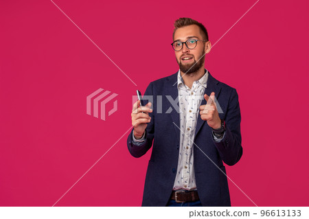 Studio shot of attractive brunette business man with glasses, in casual shirt, stylish black jacket holding a smartphone and smiling. Studio shot of attractive brunette business man with glasses, in casual shirt, stylish black jacket holding a smartphone and smiling. 96613133