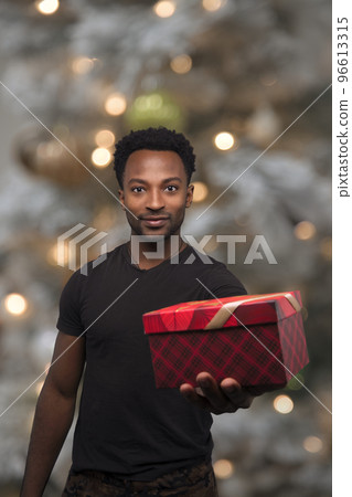 christmas present man showing surprise giving gift box holiday celebration on illuminated bokeh fir tree 96613315