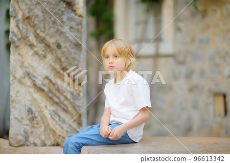 Cute preteen boy walk in Budva old town, Montenegro. Child tourist looking an ancient roman ruins. Interest in history of children. Cute preteen boy walk in Budva old town, Montenegro. Child tourist looking an ancient roman ruins. Interest in history of children. 96613342