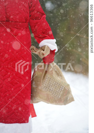 Santa Claus with bag of Christmas gifts is walking through snowy forest. Animator or parent in Santa Claus costume is rushing to a holiday for children. Traditions of winter holidays 96613366