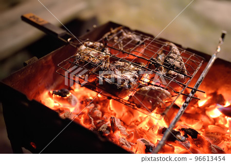 Cooking a barbecue during a weekend dinner party in the backyard. Outdoor picnic for family and friends Cooking a barbecue during a weekend dinner party in the backyard. Outdoor picnic for family and friends 96613454