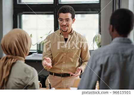 Confident multi-ethnic broker talking to intercultural colleagues 96613501