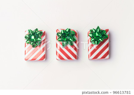 Christmas presents and new year gifts in red striped wrapping paper with green bows on white background with copy space. 96613781